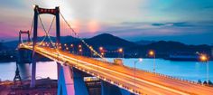 a long bridge that is over some water at night with cars driving on the road