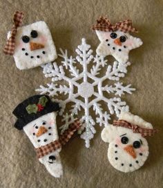 four snowmen made out of felt sitting in front of a snowflake