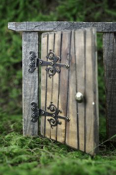 an open wooden door with metal handles in the grass