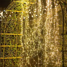 some lights that are hanging in the air near a fence and trees at night time