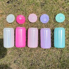 six different colored plastic cups sitting in the grass