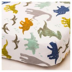 a close up of a bed sheet with dinosaurs on it and blue, green, yellow, orange, and white sheets