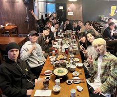 a group of young men sitting at a table with food in front of them and giving the peace sign