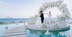 a bride and groom standing in front of an outdoor wedding ceremony arch with flowers on it