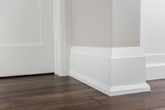 an empty room with white walls and wood flooring on the bottom part of the wall