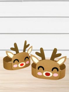 two paper reindeer headbands sitting on top of a wooden table