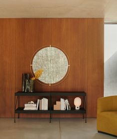 a living room with a couch, table and bookshelf in front of a wooden wall