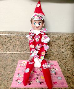 an elf is sitting on top of a piece of pink paper with hearts and flowers