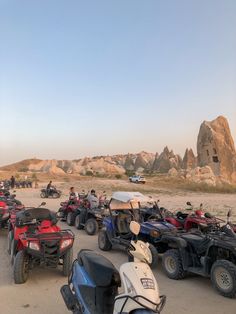 several atvs and four wheelers are parked on the sand in front of large rocks