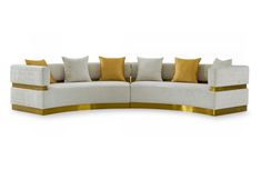 a curved couch with gold trim and pillows on the back, sitting in front of a white background