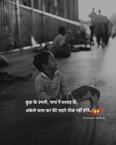 a little boy sitting on the ground next to a dog and looking up at something