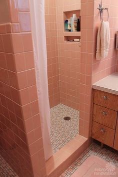 a bathroom with pink tile walls and flooring is shown in this image, there is a shower stall next to the sink