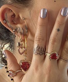 a close up of a person with tattoos on their fingers and wearing ear piercings