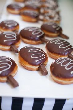 chocolate covered donuts with white icing on a plate and black and white striped tablecloth