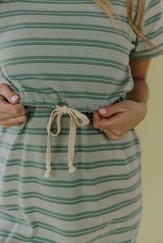 a woman wearing a green and white striped dress with her hands in her pockets,