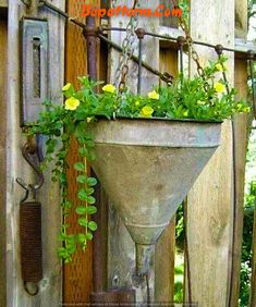 a planter filled with yellow flowers sitting on top of a wooden fence covered in vines