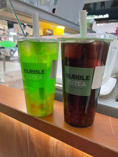 two drinks sitting on top of a counter next to each other in front of a window