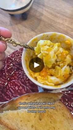 a person is holding a spoon over a bowl of food on a plate with bread