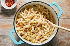 macaroni and cheese in a blue pot with a wooden spoon next to it