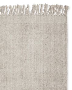 a beige rug with fringes on the top and bottom, against a white background