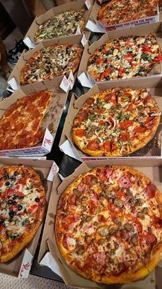 many different pizzas are in boxes on the table