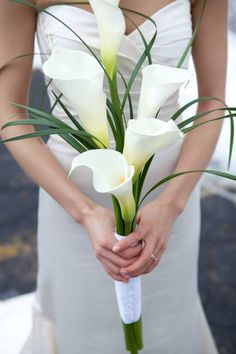 a bride holding a bouquet of white calla lilies