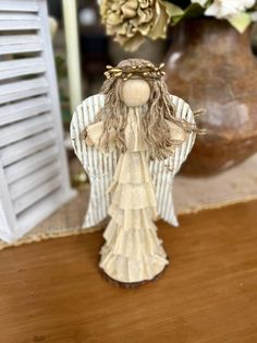 an angel figurine sitting on top of a wooden table next to some flowers