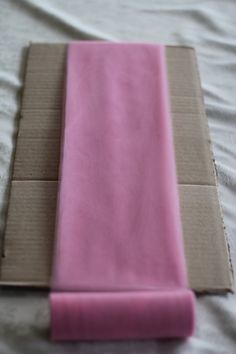 the pink cloth is folded on top of the cardboard