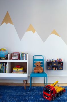 a child's room with mountains painted on the wall and toy cars sitting on the floor