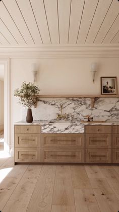 a kitchen with marble counter tops and wooden cabinets, along with a vase filled with flowers