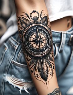 a woman's arm with a compass and feathers tattoo design on her left arm