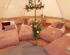 the inside of a tent with four beds and flowers