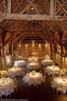 the inside of a barn with tables and chairs set up for a wedding reception in white linens