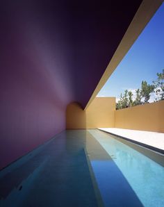 an empty swimming pool in the middle of a building with purple walls and blue water