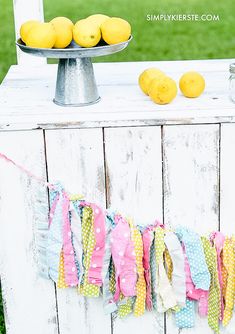 some lemons are sitting on top of a table with ribbons around it and a cake stand in the background