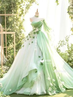 a green and white wedding dress on display in a room with greenery behind it