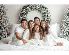 a family sitting on a bed in front of christmas wreaths