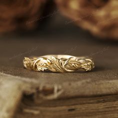 a gold wedding ring sitting on top of a wooden table next to an old book