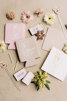 the wedding stationery is laid out with flowers and cards on top of each other