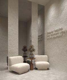 two white chairs sitting next to each other in front of a wall with writing on it