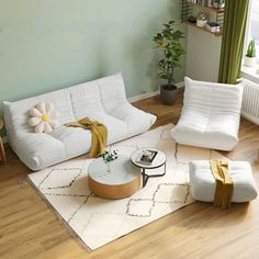 a living room filled with white furniture and wooden flooring next to a green wall