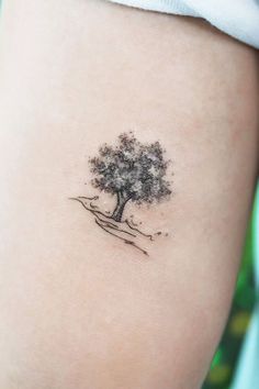 a small tree tattoo on the back of a woman's right arm and leg