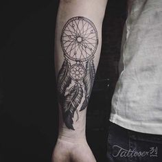 a man with a tattoo on his arm holding a hand and a dream catcher in the middle