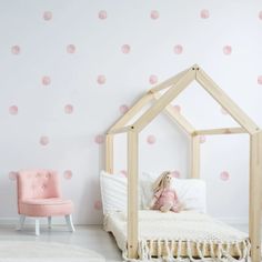 a child's room with pink polka dot wallpaper and a wooden doll house bed