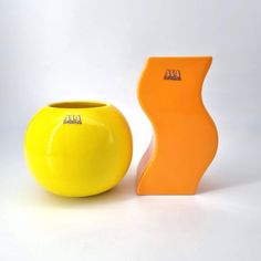 a yellow vase sitting next to an orange vase on a white surface with the word art written on it