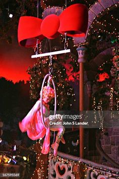 a woman hanging from a swing in front of christmas lights