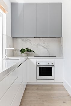 a kitchen with white cabinets and marble counter tops, along with a stainless steel oven