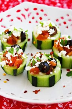 cucumbers with olives, tomatoes and feta cheese are arranged on a white plate