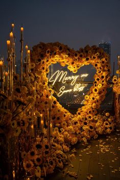 a heart - shaped frame with flowers and candles in the shape of a sunflower