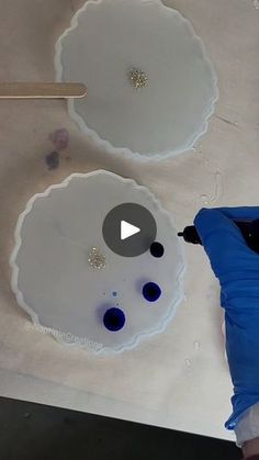 a person is painting on the ceiling with white paint and blue glass bottles in front of them